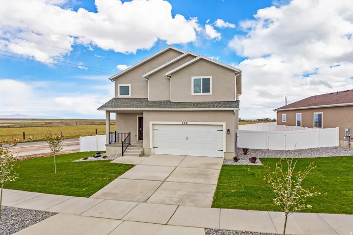 Contemporary stucco exterior with a two-car garage, front porch, and a gravel-lined side yard