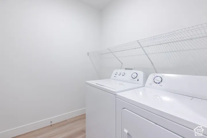 Laundry area featuring a wire shelving unit and wood-finish flooring