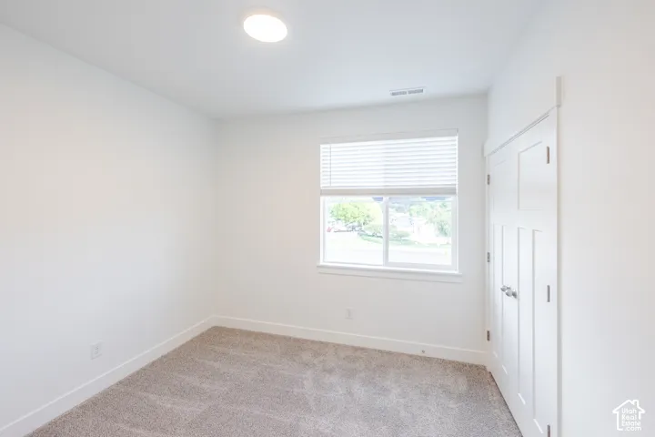 Recessed ceiling light, neutral wall paint, window with blinds, paneled door, and carpeted flooring