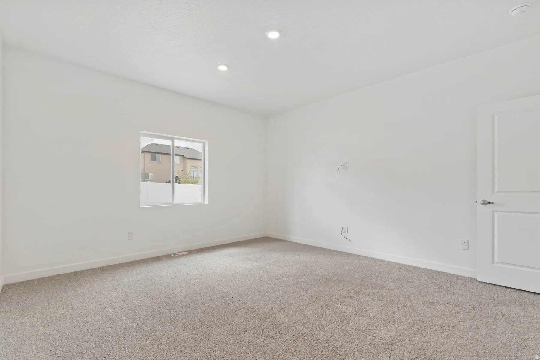 Carpeted interior space featuring white walls and a single window with a white frame