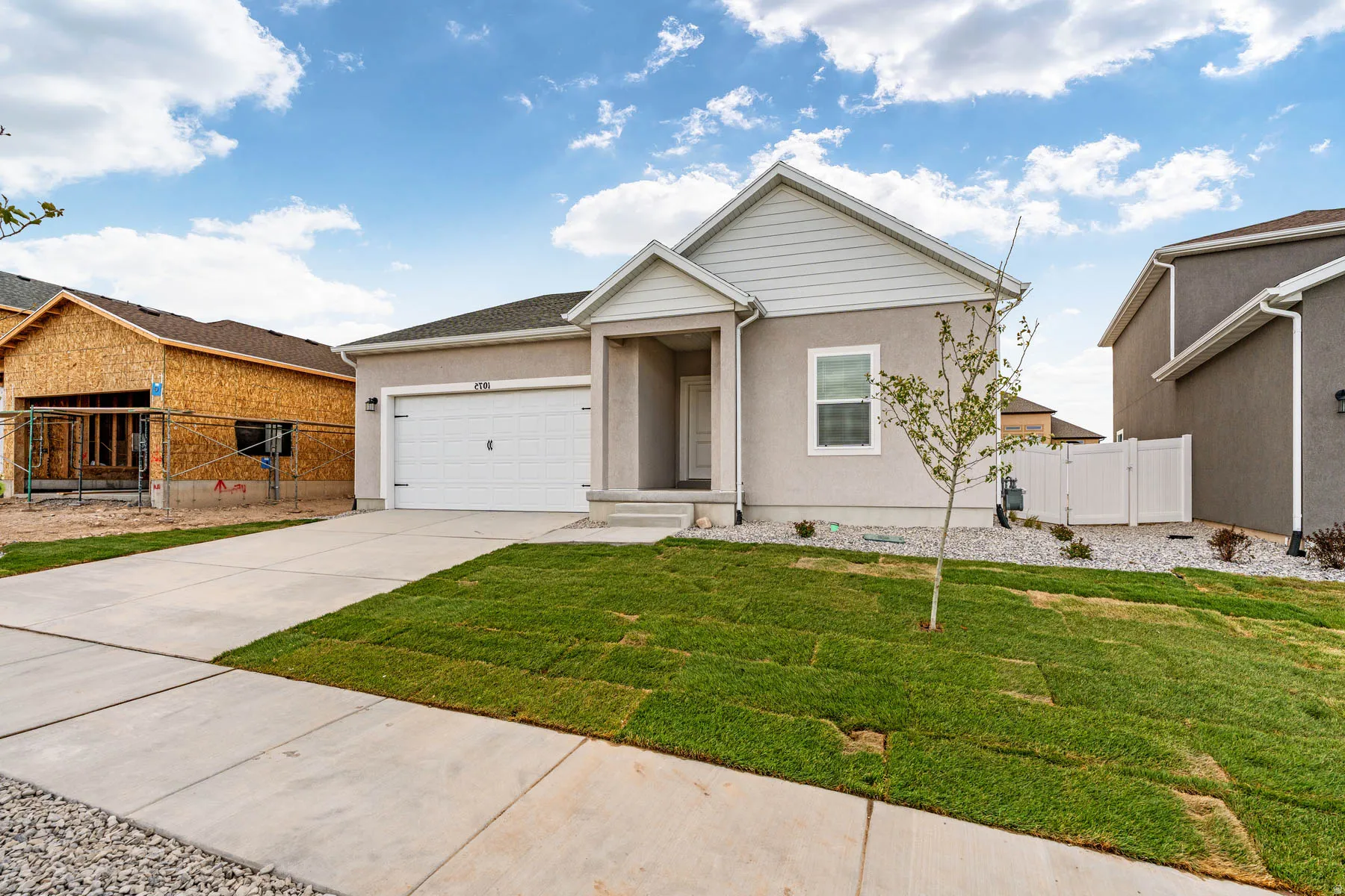 Contemporary stucco exterior featuring a white garage door and a covered entryway