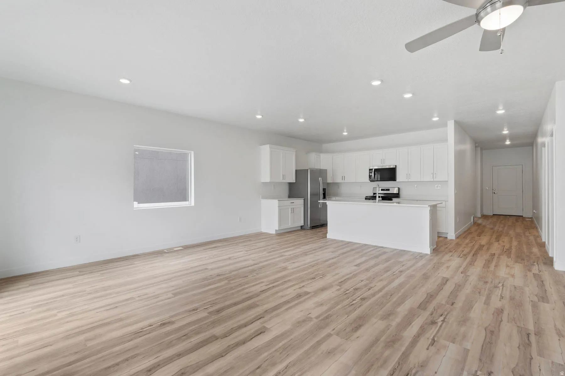 Open-concept living space featuring wood-finish flooring, recessed lighting, and a modern ceiling fan