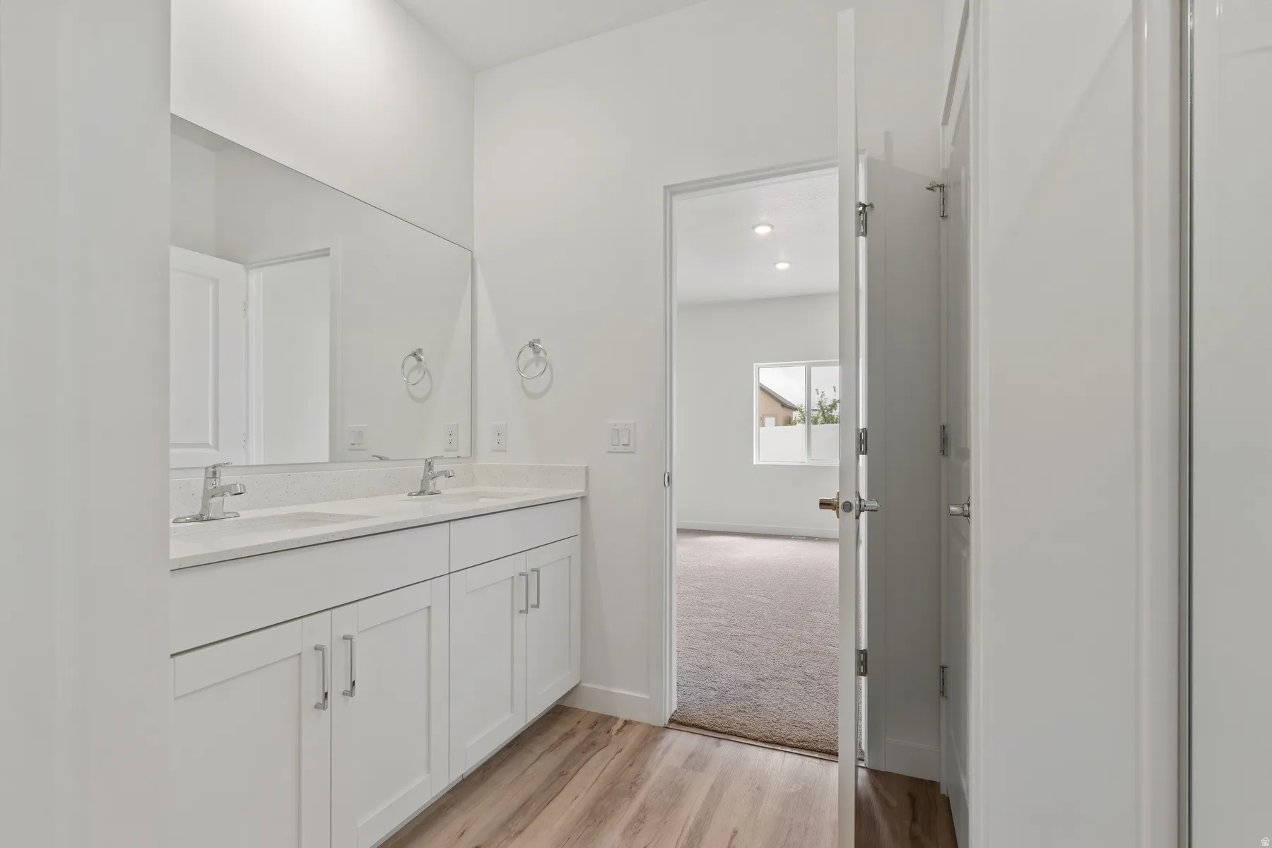 Dual vanity with white cabinetry, integrated sinks, chrome faucets, and a large wall-mounted mirror