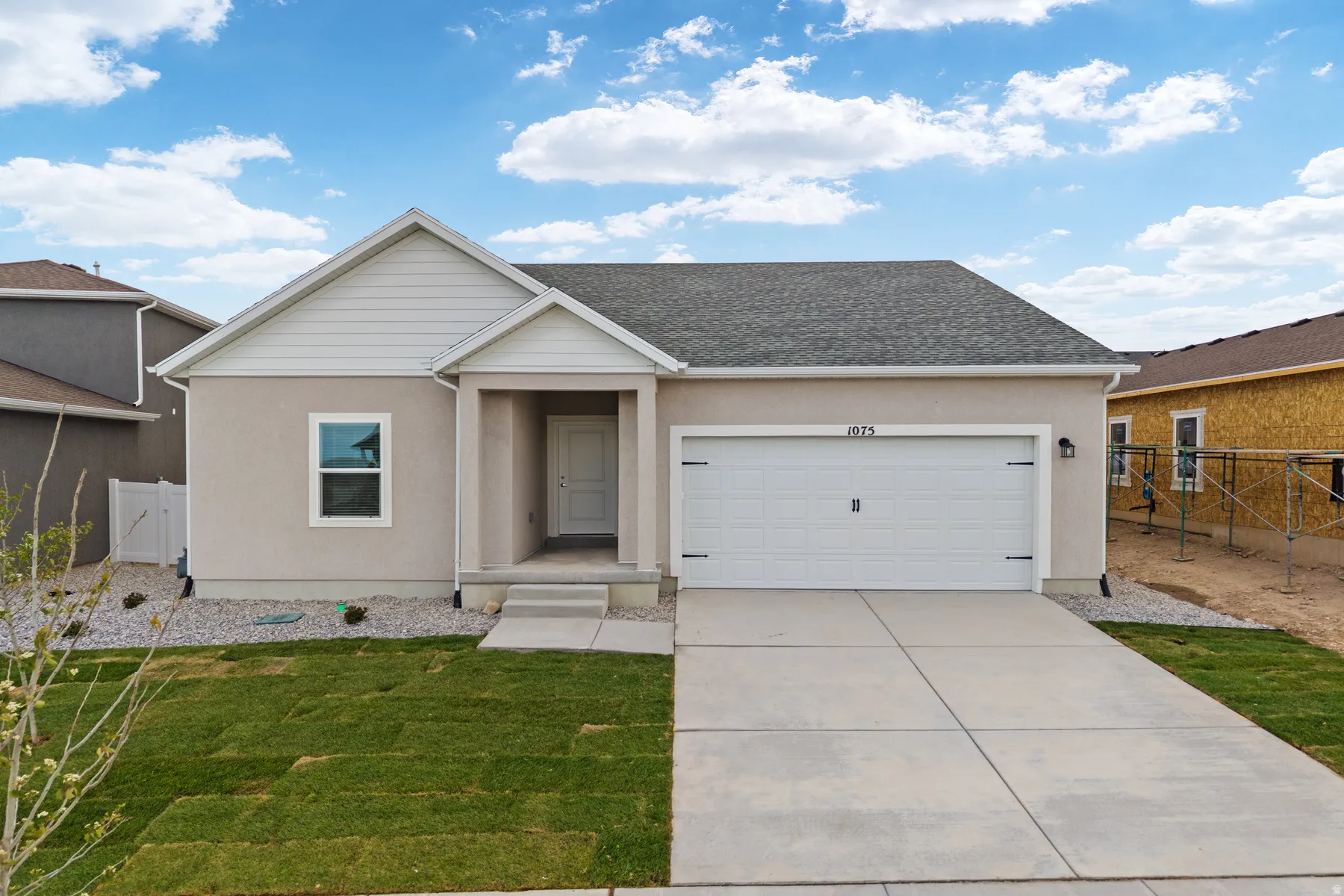 Contemporary stucco exterior with an attached garage, a covered entry, and a newly sodded lawn
