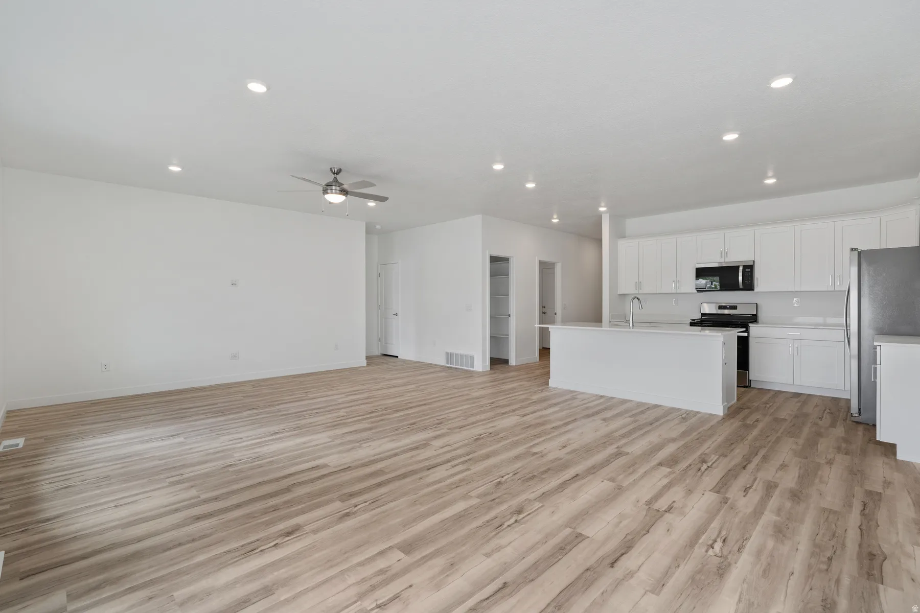 Open-concept living area featuring wood-finish flooring, recessed lighting, and a ceiling fan