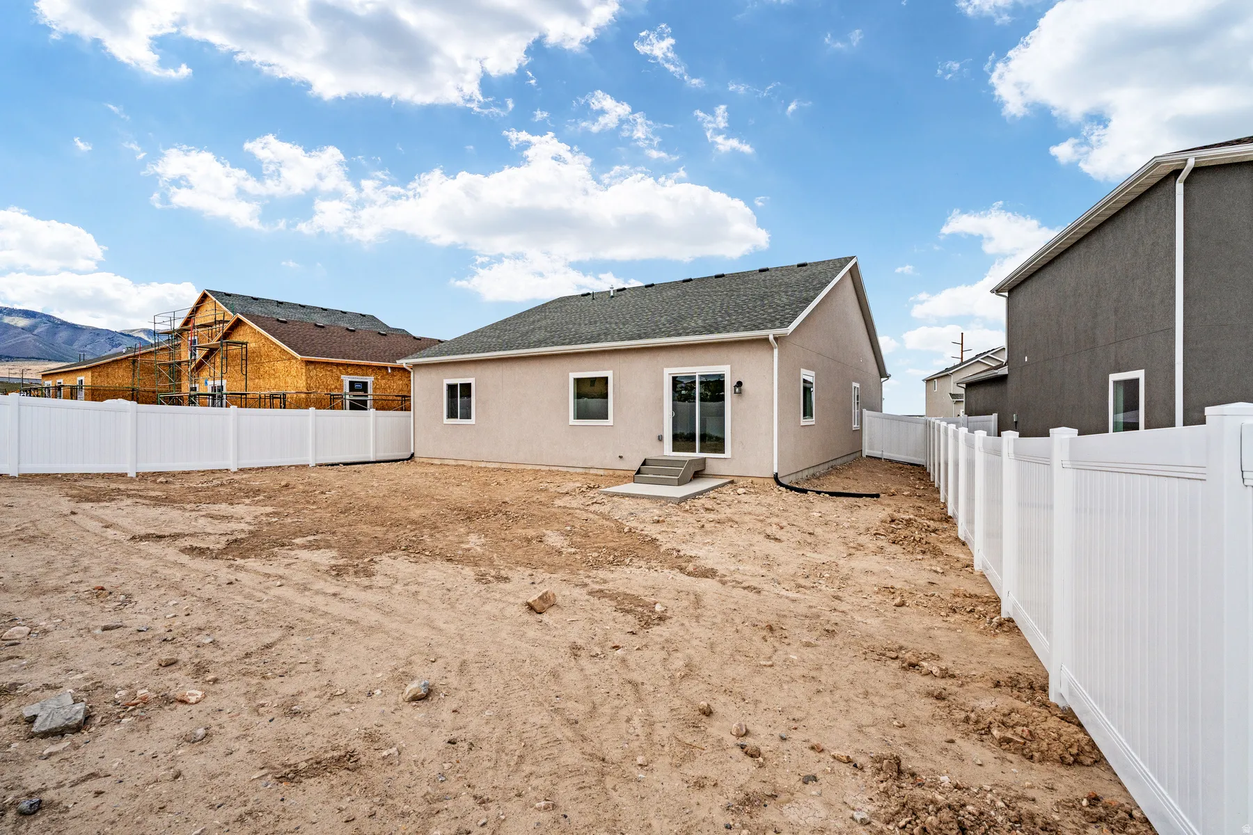 Rear exterior featuring a stucco finish and a dark shingle roof