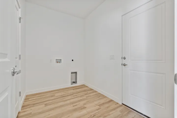 Dedicated utility space featuring light wood-finish flooring, white baseboards, and bright white walls
