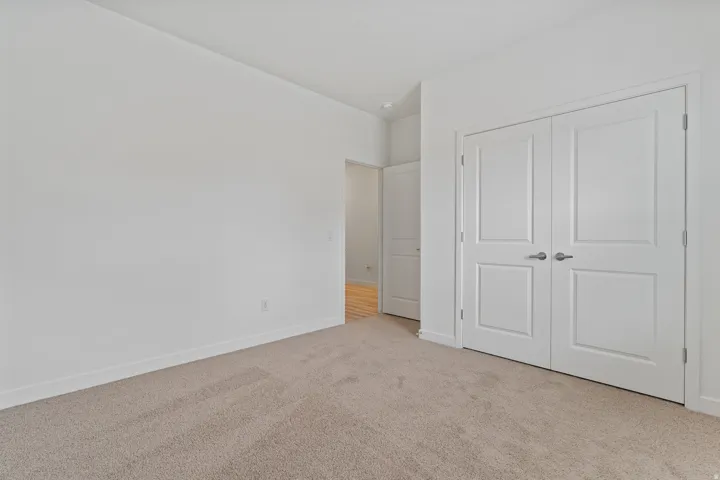Neutral tone wall paint with white trim, light-colored carpet flooring, and white paneled double doors