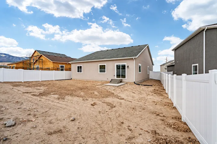 Rear exterior featuring a stucco finish and a dark shingle roof