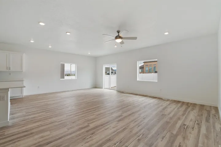 Spacious open-concept room featuring wood-finish flooring, recessed lighting, and a ceiling fan