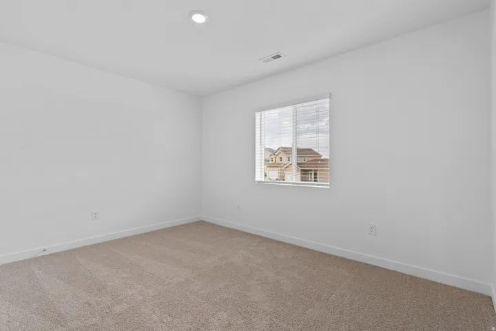 Carpeted room featuring a single window with blinds, recessed lighting, white walls, and white baseboards