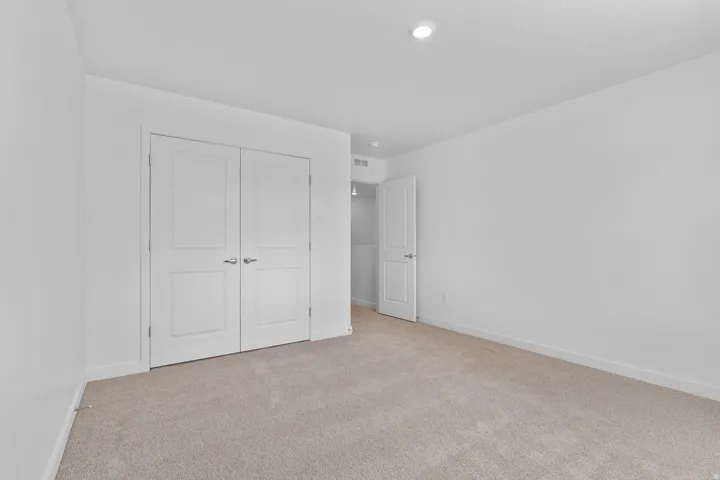 Bedroom featuring neutral carpeting, white walls, recessed ceiling lighting, and a double-door closet with paneling