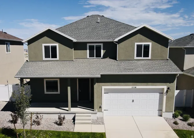 Contemporary two-story residence with stucco exterior, attached two-car garage, covered porch, and gravel landscaping