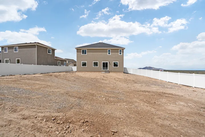 Spacious lot with a two-story residence featuring a neutral stucco exterior, white window trim, and a dark roof