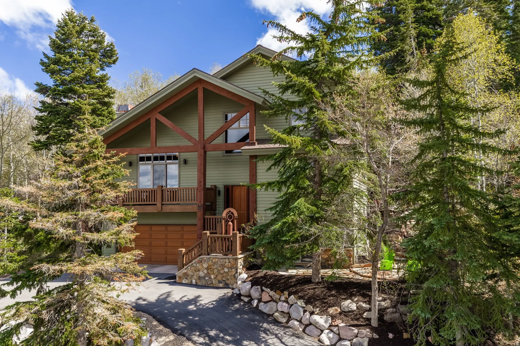 Mountain-style residence featuring a prominent timber frame facade and light green siding