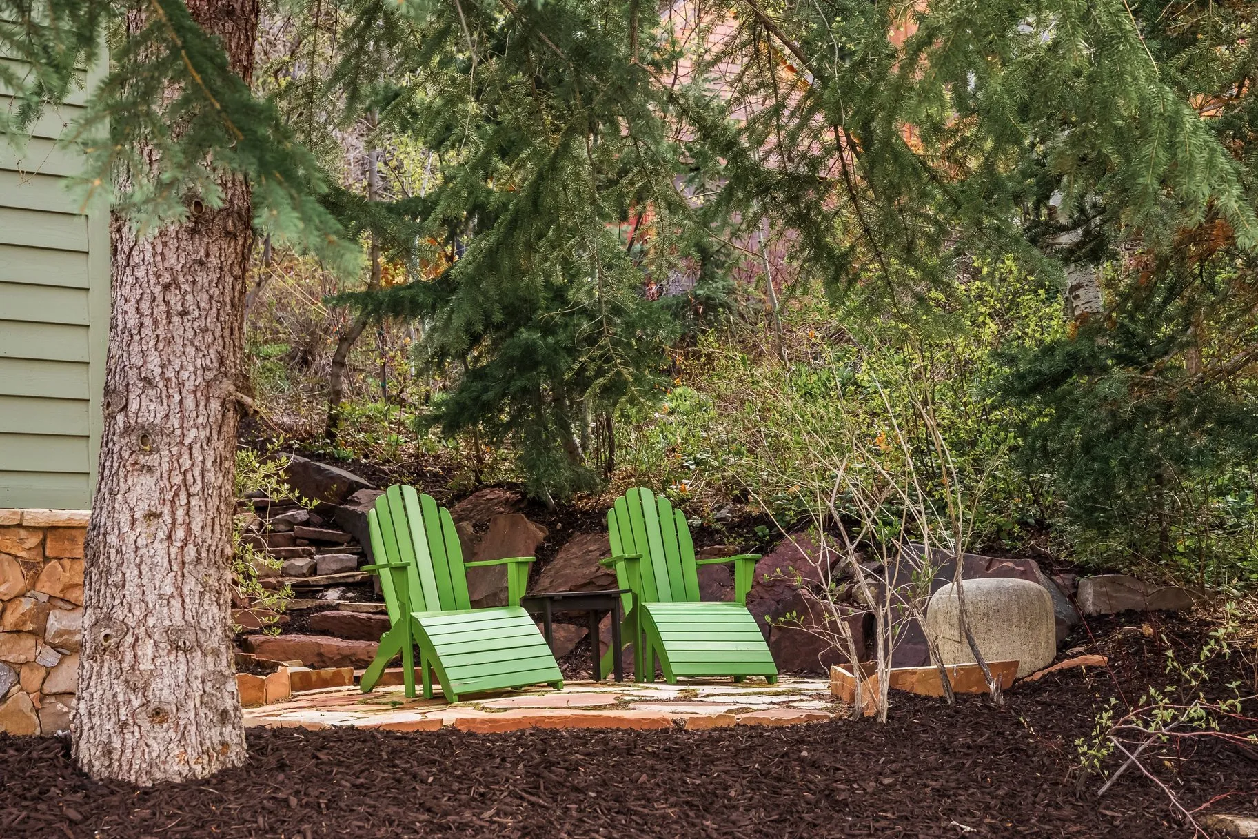 Stone retaining wall and natural rock landscaping complement the outdoor patio area