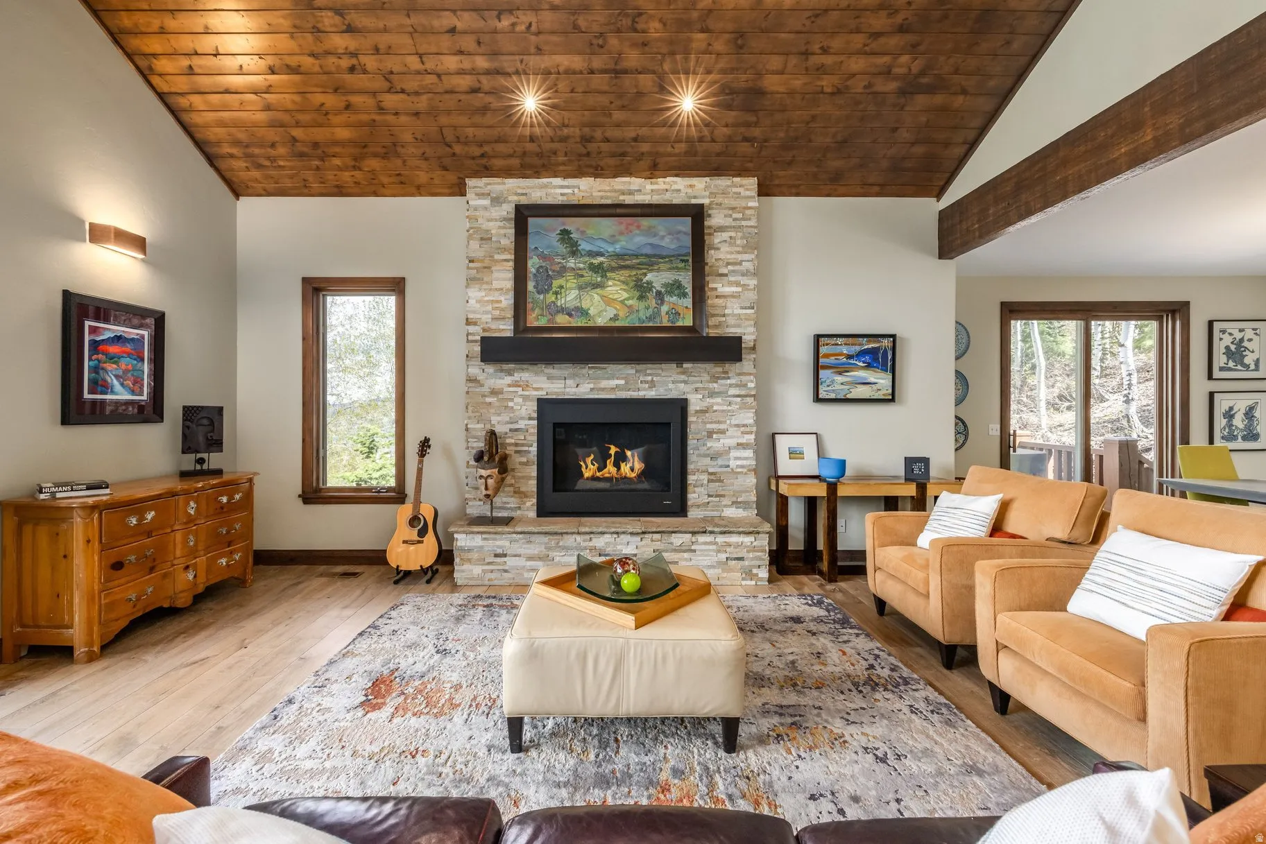 Living area featuring a stone-clad fireplace with a dark wood mantle, wood-finish flooring, and a vaulted wood-plank ceiling