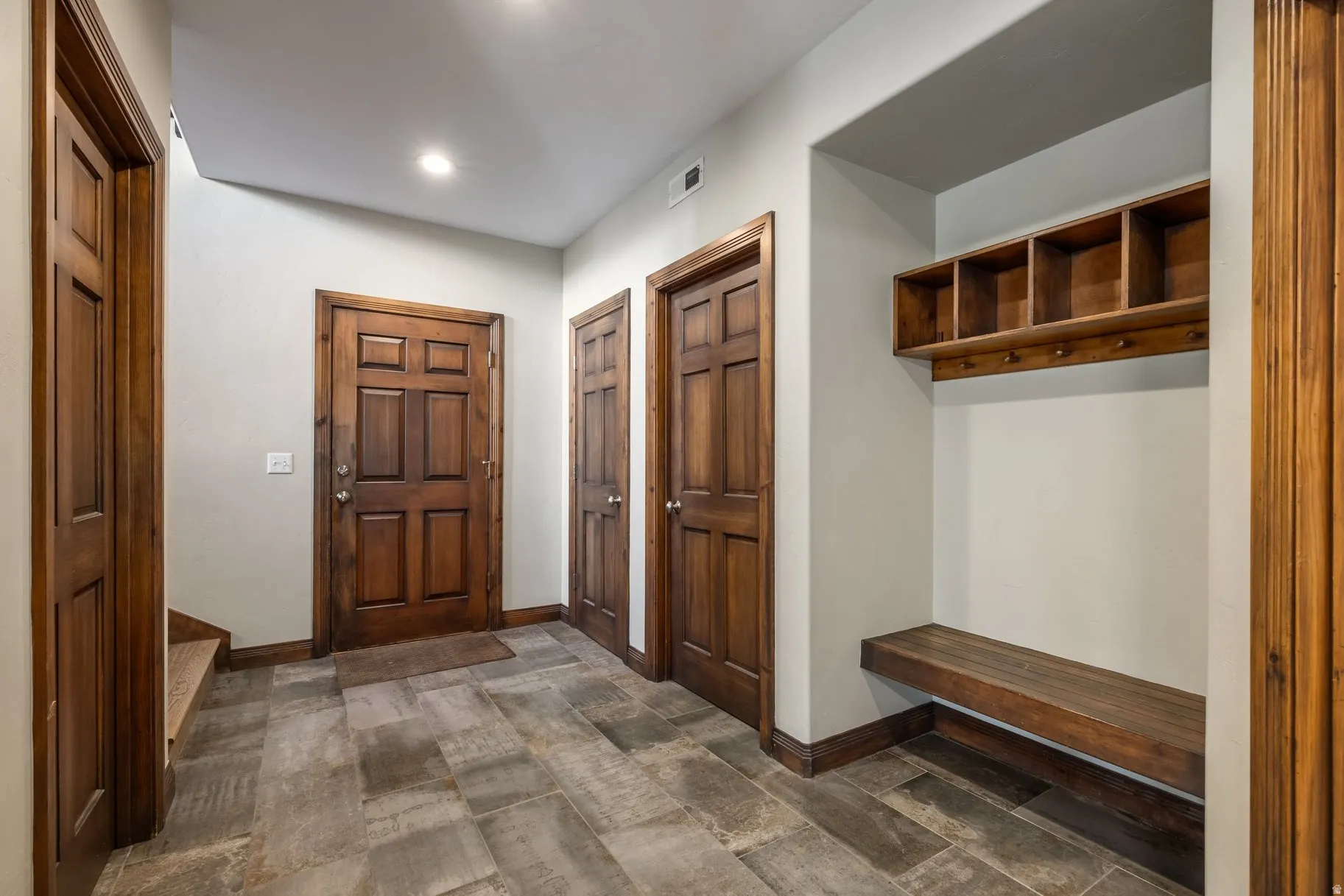 Entryway featuring wood-finish panel doors, plank tile flooring, and recessed lighting