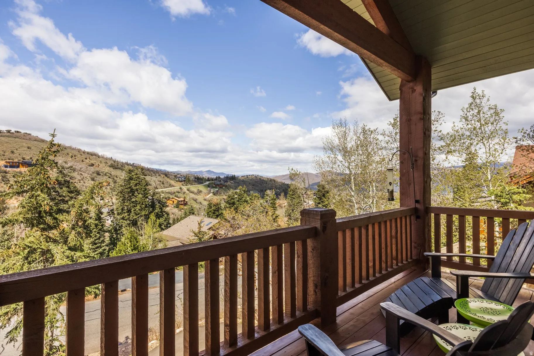 Expansive outdoor deck featuring wood-finish flooring, a sturdy wood railing, and exposed wooden beams