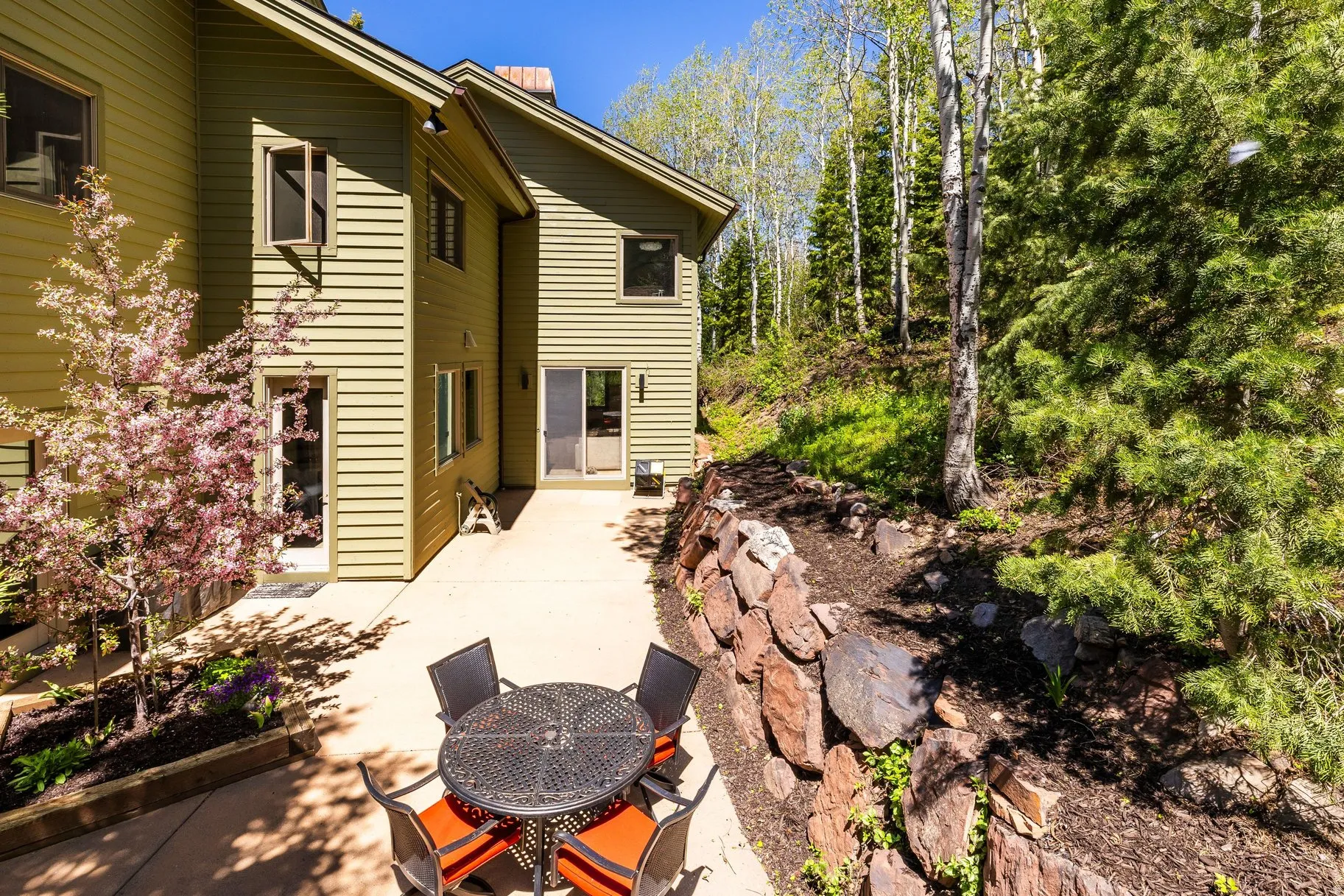 Spacious outdoor patio with a stone retaining wall and a mature flowering tree