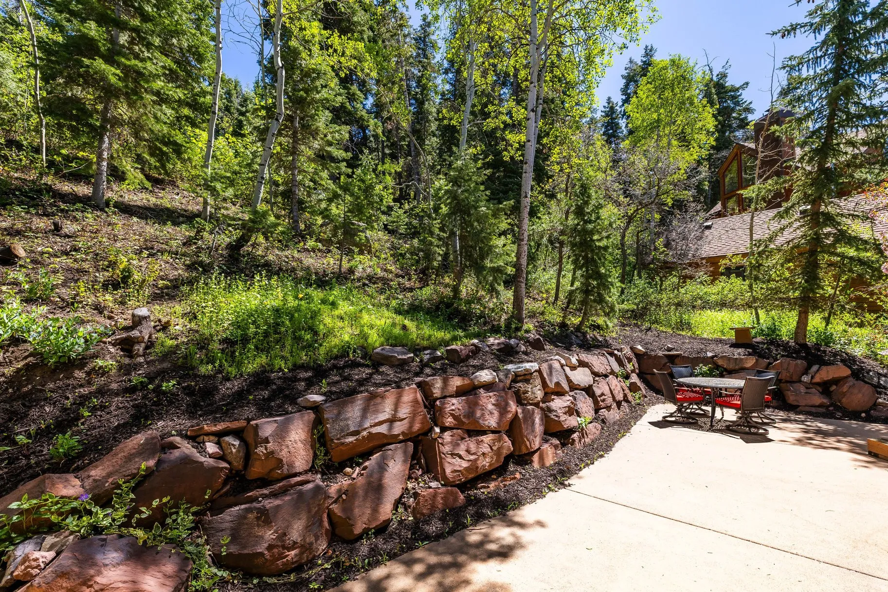 Expansive outdoor patio area featuring a stone retaining wall and concrete paving