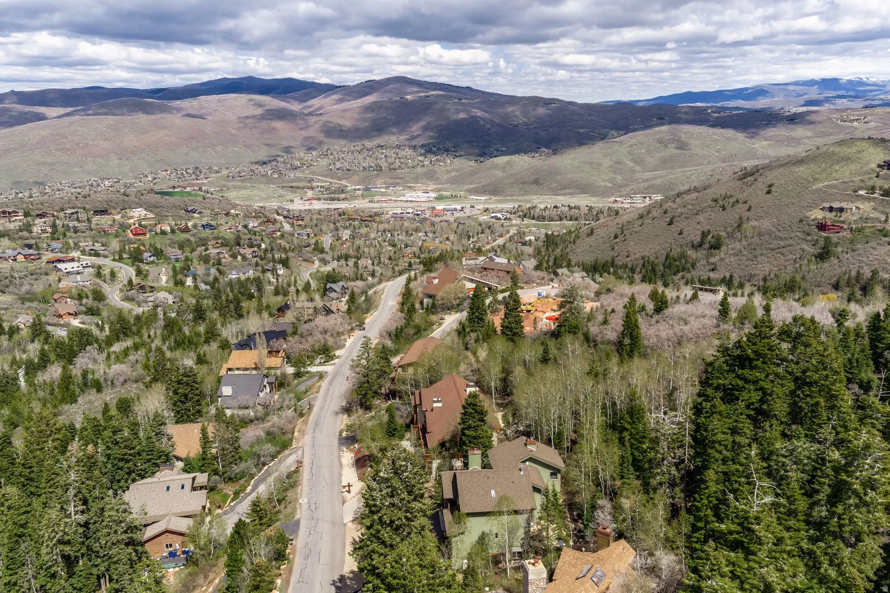 Elevated mountain community featuring a paved road, dense evergreen and deciduous trees, and numerous residential properties