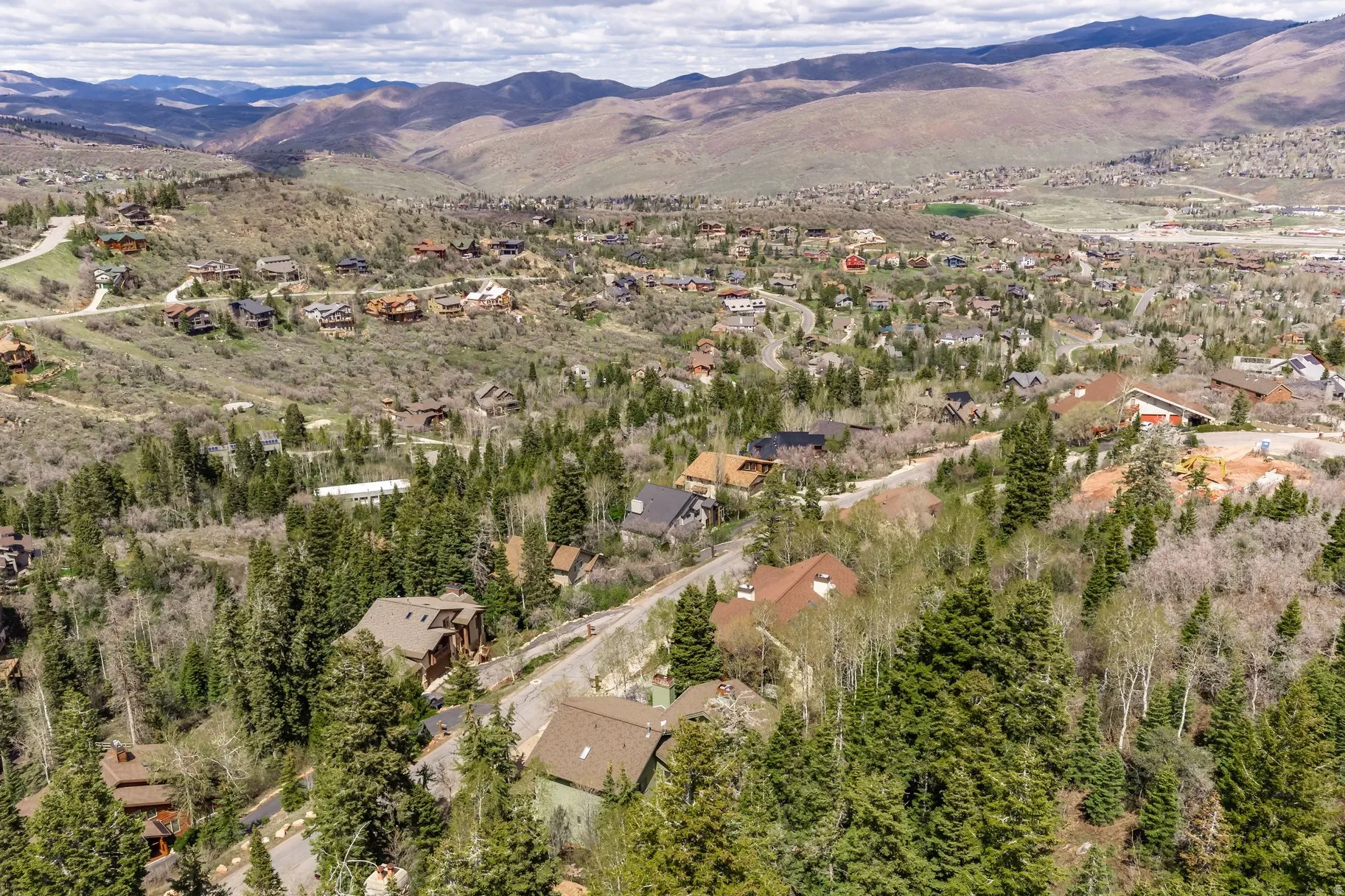 Expansive mountain community featuring diverse architectural styles, mature evergreen and deciduous trees, and winding roadways