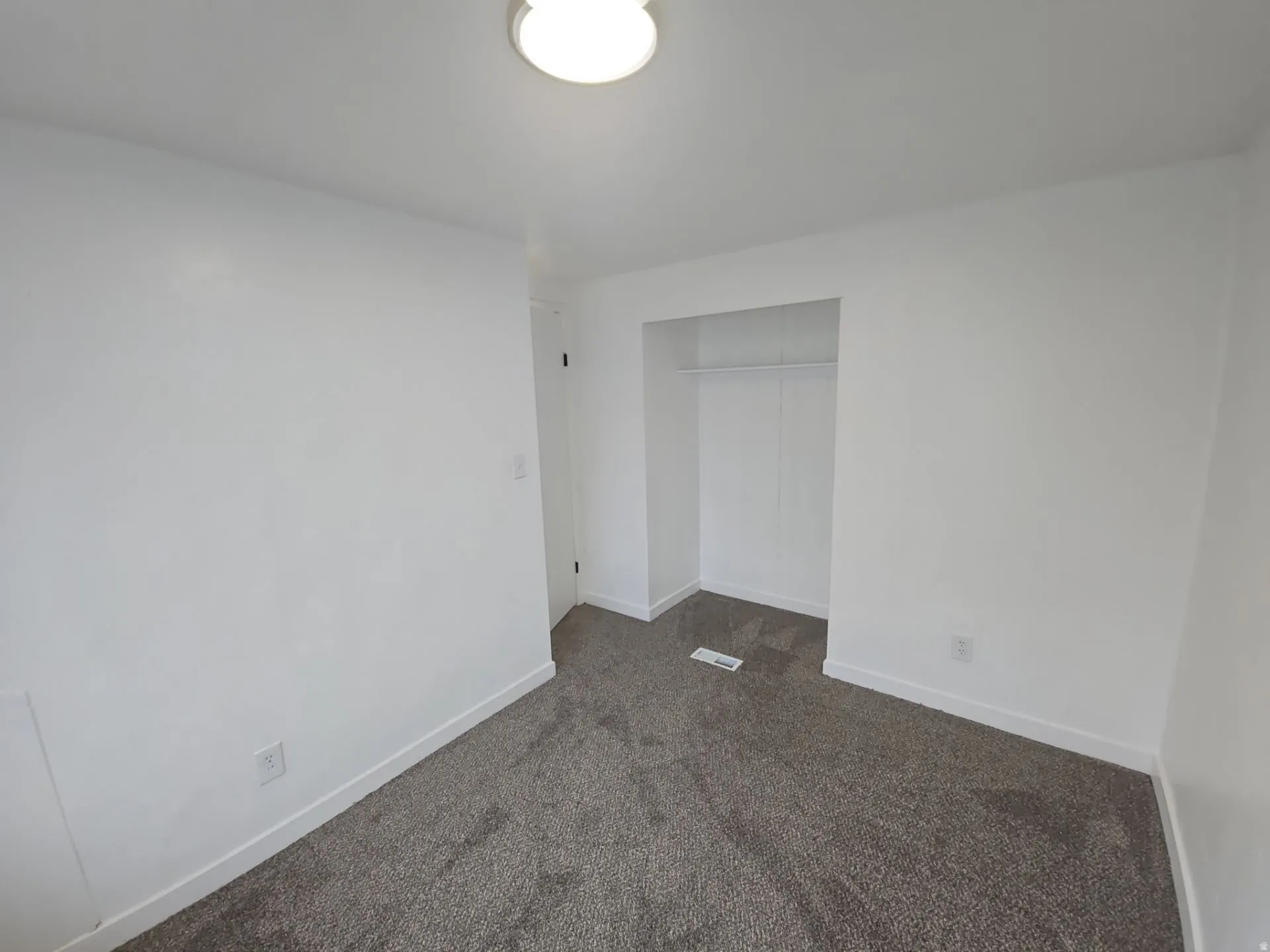 Unfurnished bedroom with dark carpet and a closet