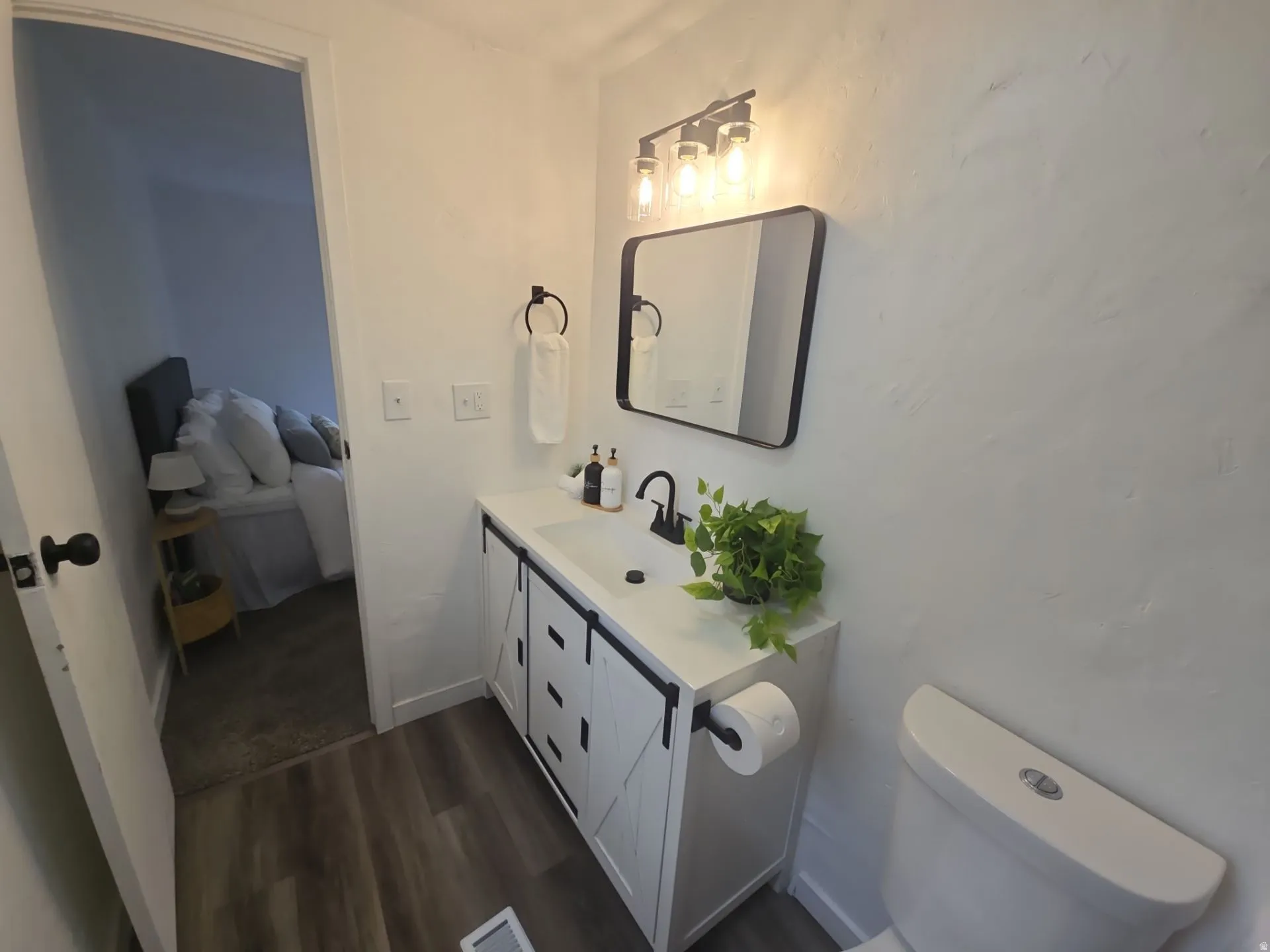 Half bath with vanity, connected bathroom, and dark wood-style flooring