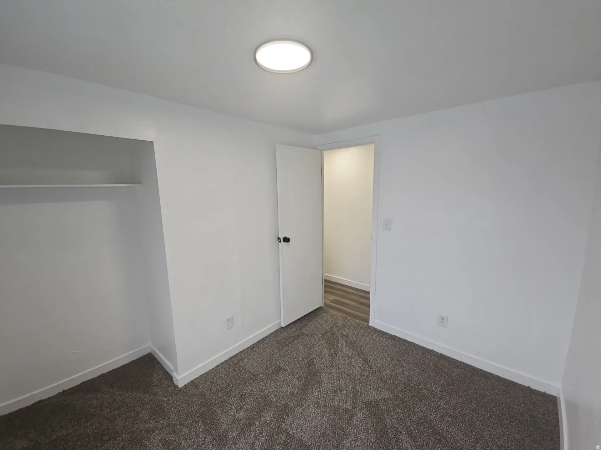 Unfurnished bedroom featuring dark carpet and a closet