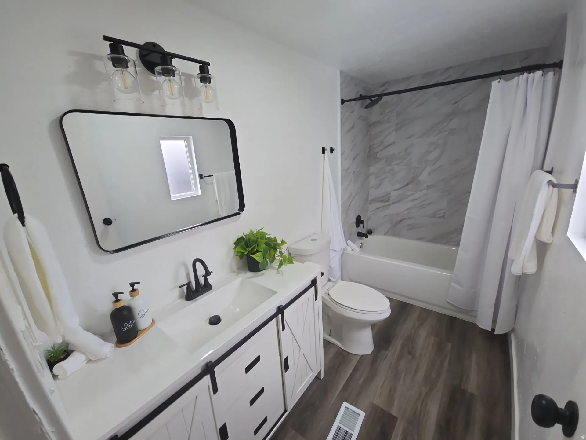 Full bath with vanity, shower / bath combo with shower curtain, and dark wood-style flooring