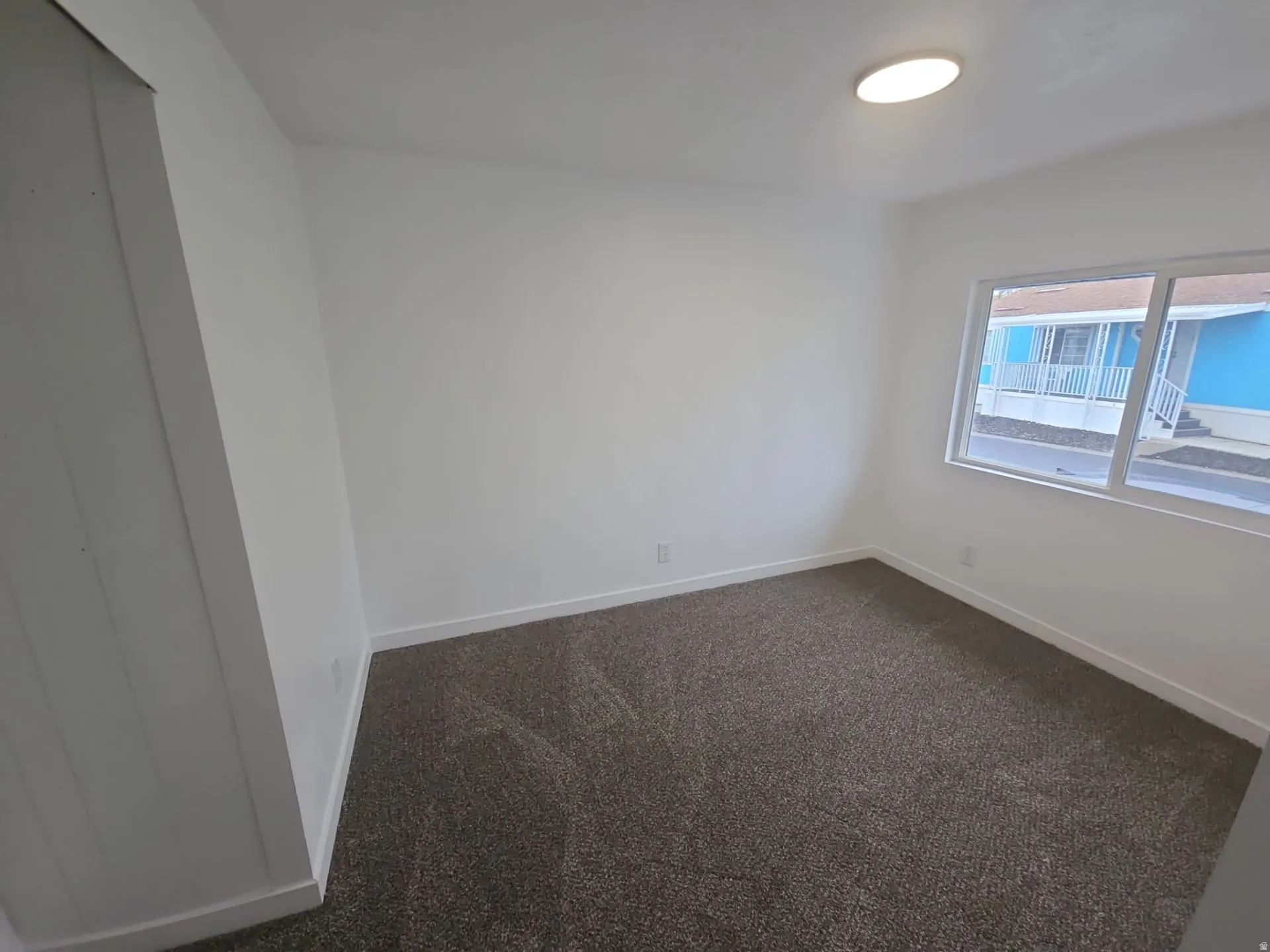 Unfurnished room featuring dark colored carpet and baseboards