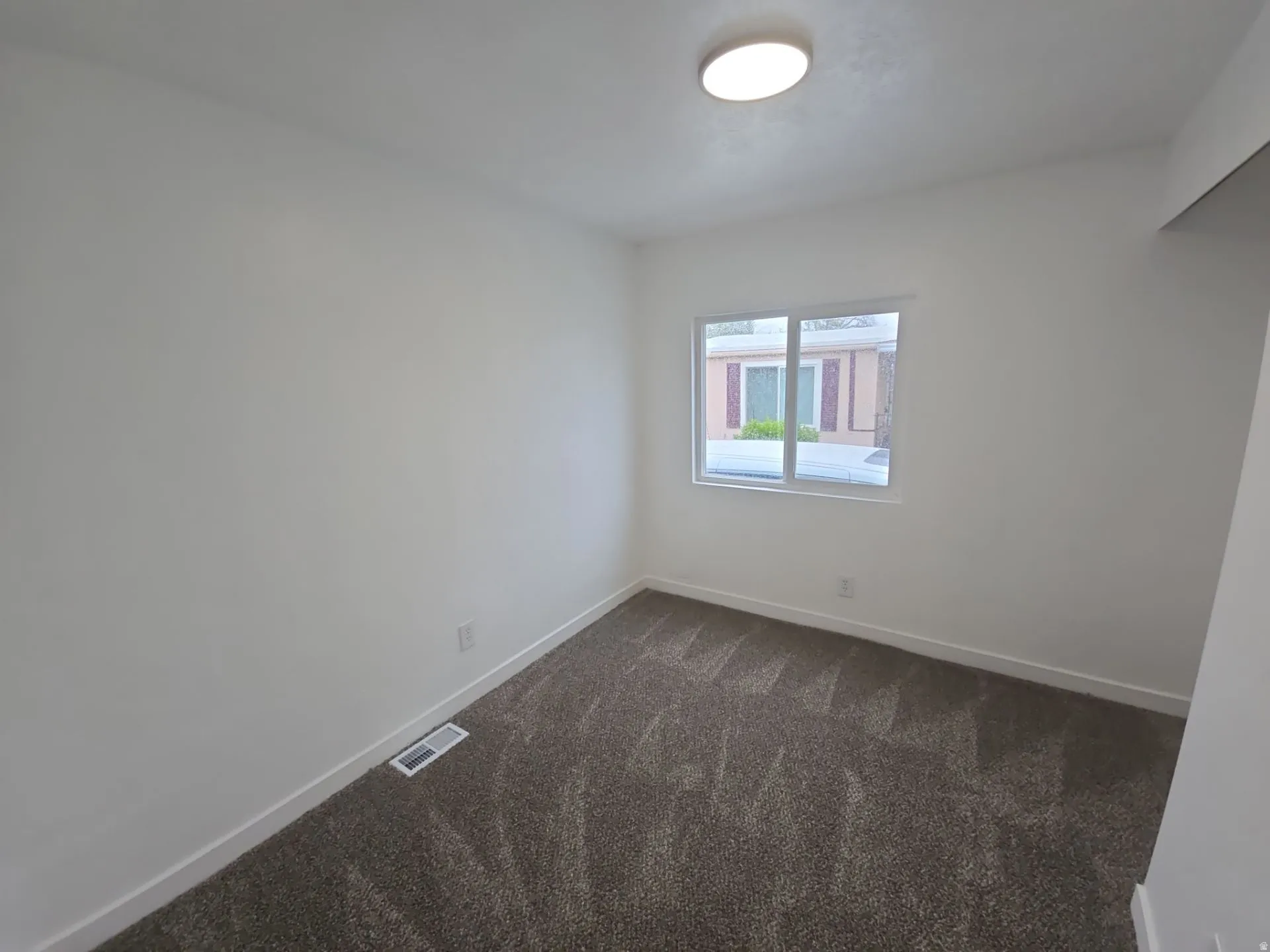 Empty room with dark carpet and baseboards