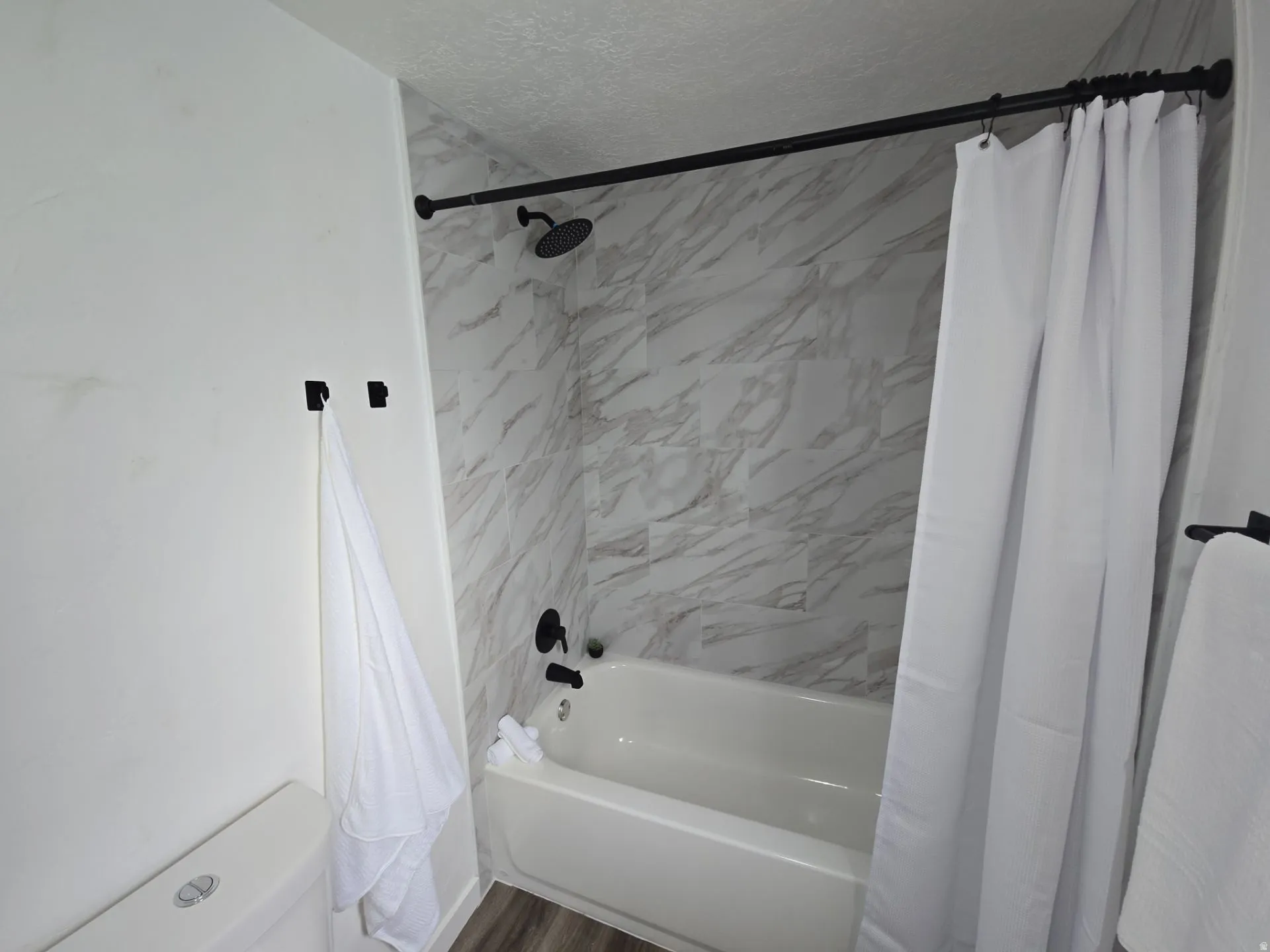 Full bath with shower / tub combo with curtain and a textured ceiling