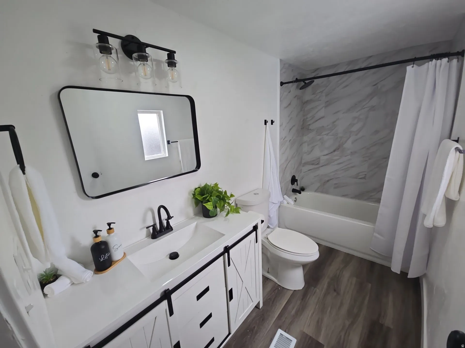 Bathroom with vanity, shower / bath combination with curtain, and dark wood-style floors