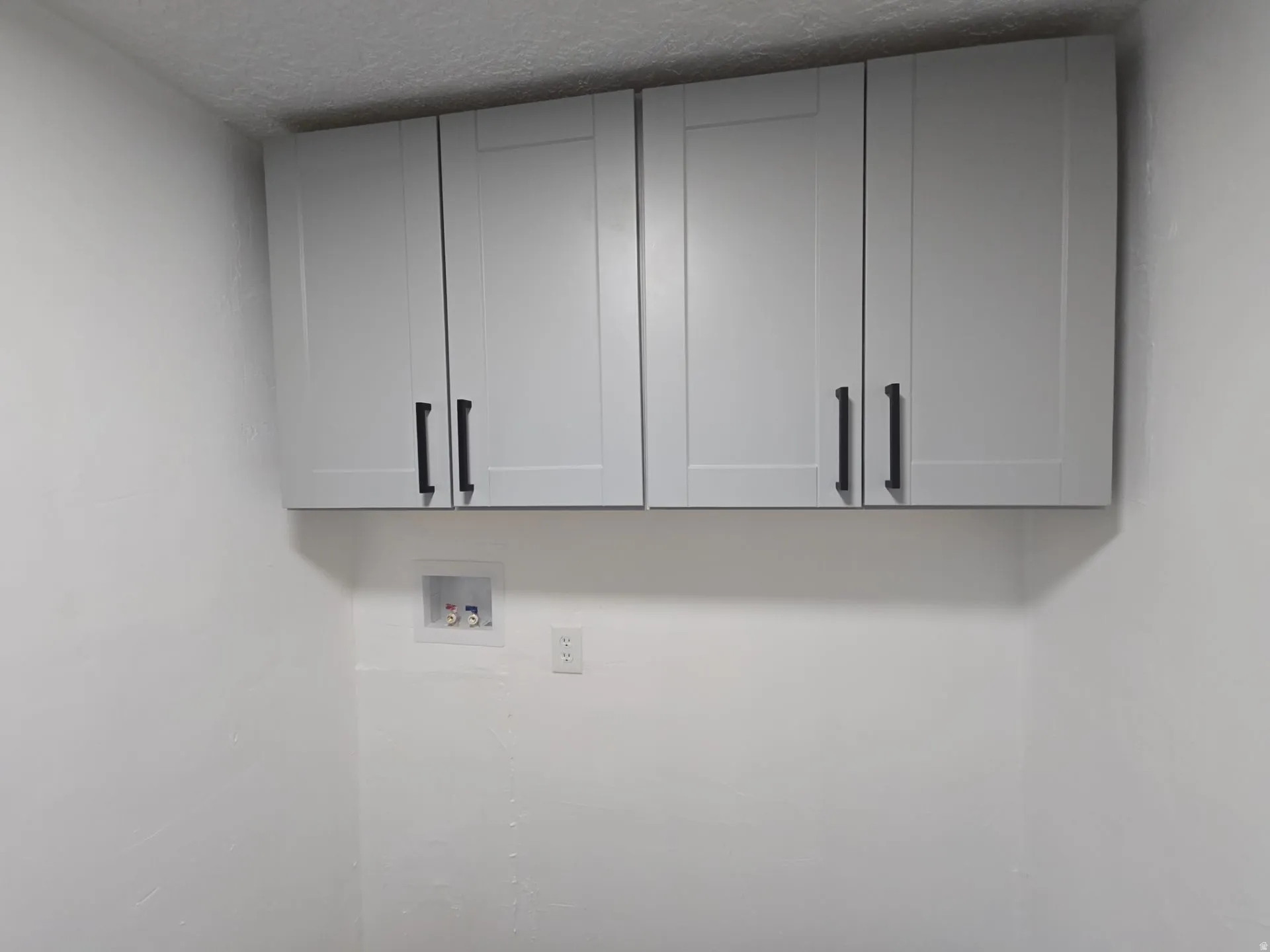 Laundry area with cabinet space, hookup for a washing machine, and a textured ceiling