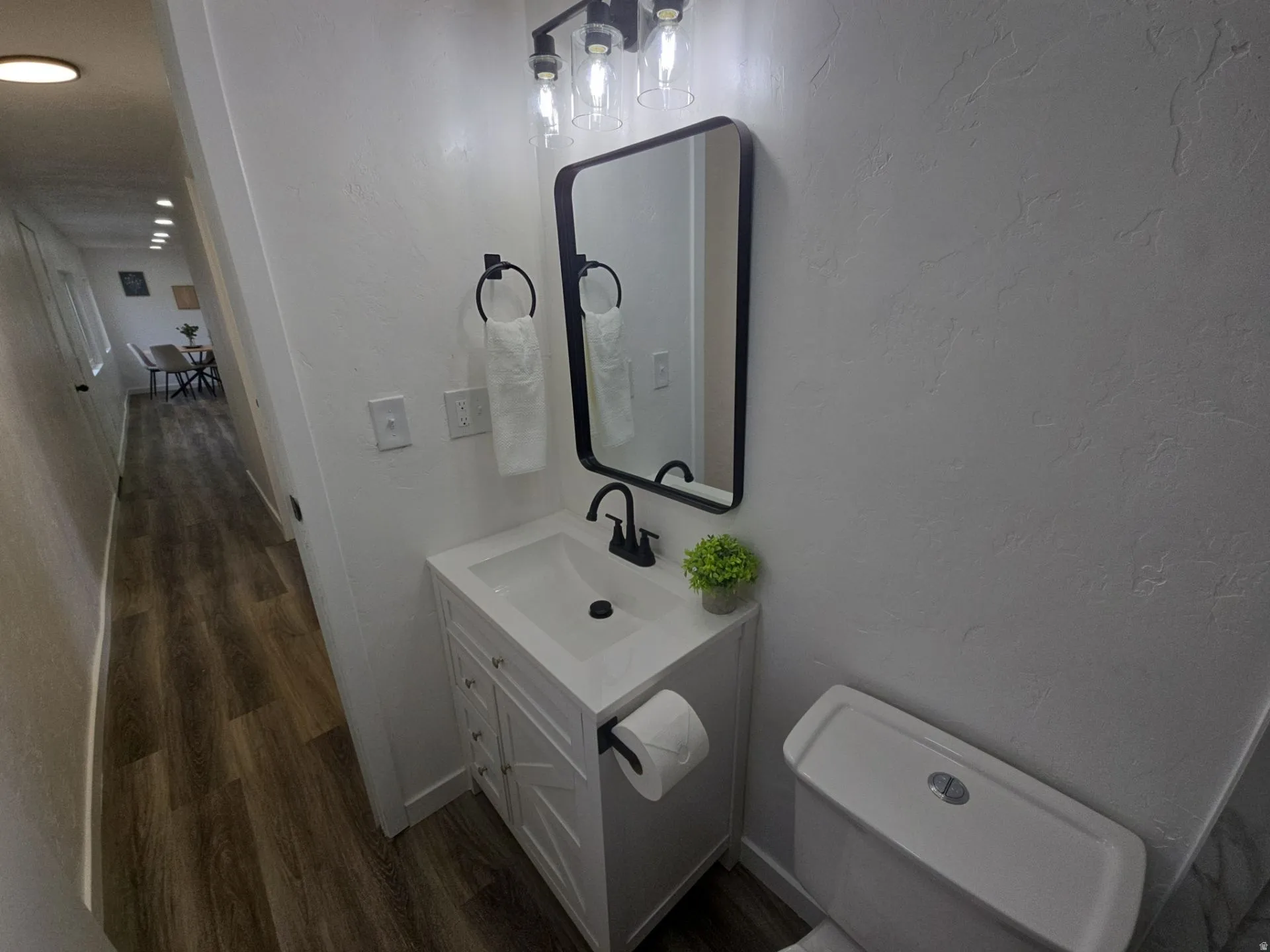 Bathroom with vanity, a textured wall, and dark wood-style floors