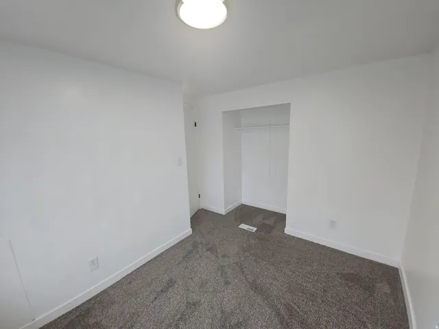 Unfurnished bedroom with dark carpet and a closet