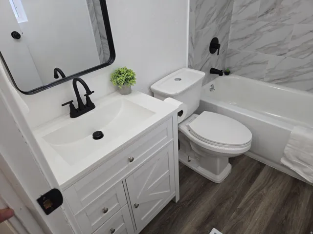 Full bath featuring vanity, dark wood-style floors, and shower / bath combination