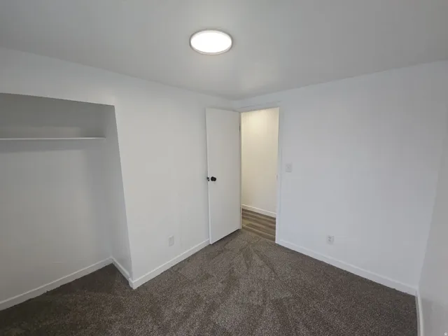 Unfurnished bedroom featuring dark carpet and a closet