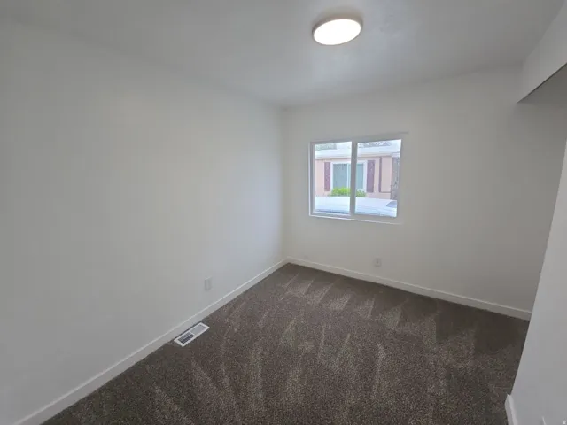 Empty room with dark carpet and baseboards