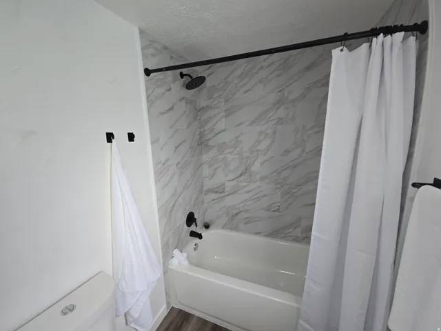 Full bath with shower / tub combo with curtain and a textured ceiling