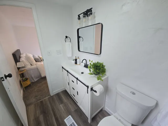 Half bathroom with ensuite bathroom, vanity, and dark wood finished floors