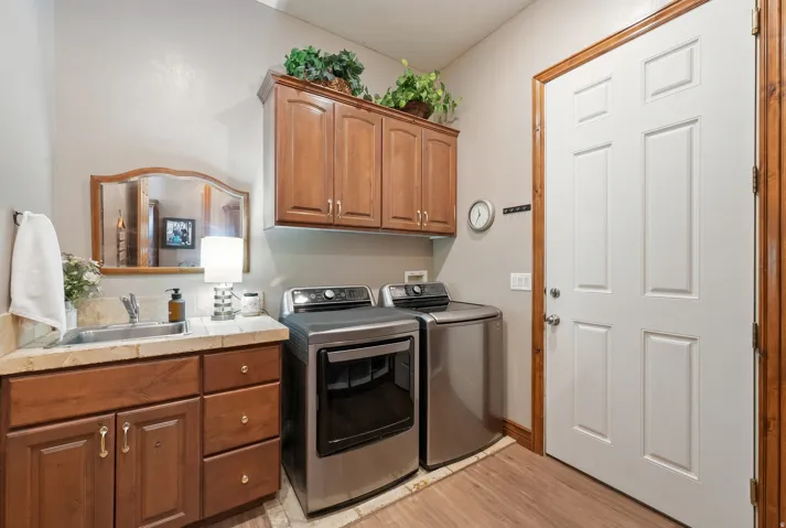 Laundry room with cabinet space, washing machine and dryer, and light wood-style flooring