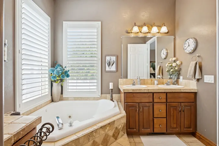 Full bathroom with double vanity, a jetted tub, healthy amount of natural light, and light tile patterned floors