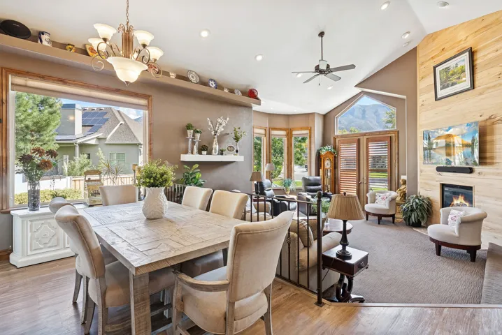 Dining room featuring lofted ceiling, a glass covered fireplace, ceiling fan, light wood finished floors, and hanging lights