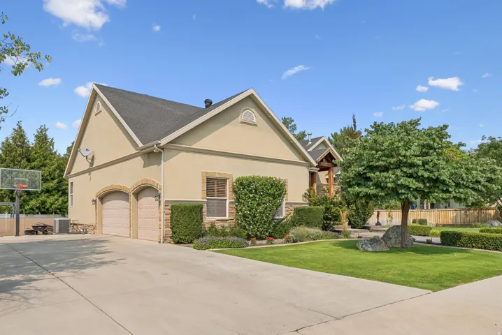 View of side of home with stucco siding, driveway, stone siding, and an attached garage
