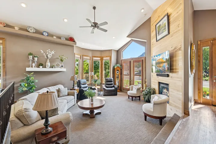 Living room featuring lofted ceiling, a fireplace, ceiling fan, wood finished floors, and recessed lighting