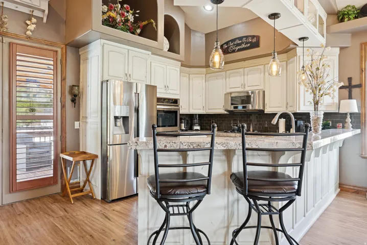 Kitchen with a kitchen bar, stainless steel appliances, pendant lighting, a peninsula, and tasteful backsplash