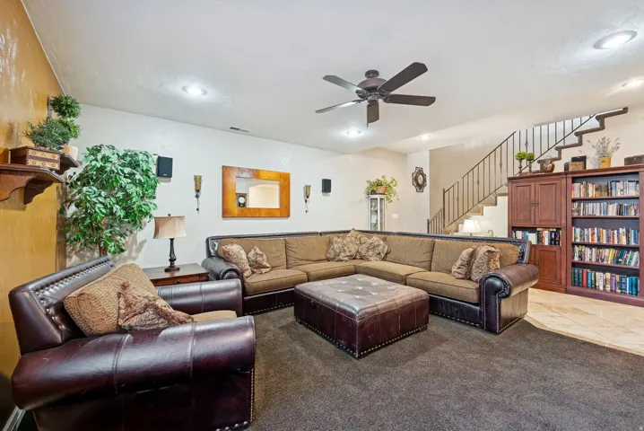 Living room featuring a ceiling fan, carpet flooring, and tile patterned floors